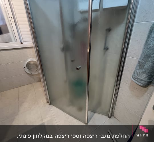 מקלחון זכוכית עם דלתות מתכת בחדר אמבטיה